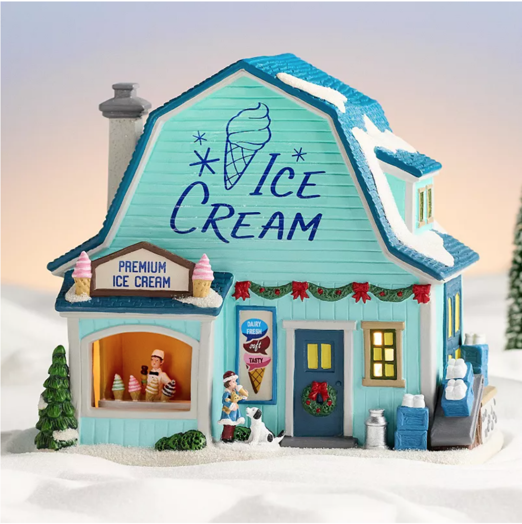 Image of Christmas village house that looks like a charming ice cream parlor. Color is mint green, says "ice cream", and "premium ice cream" Boy is in the window selling ice cream cones and little girls is out front of the ice cream shop with a dog.