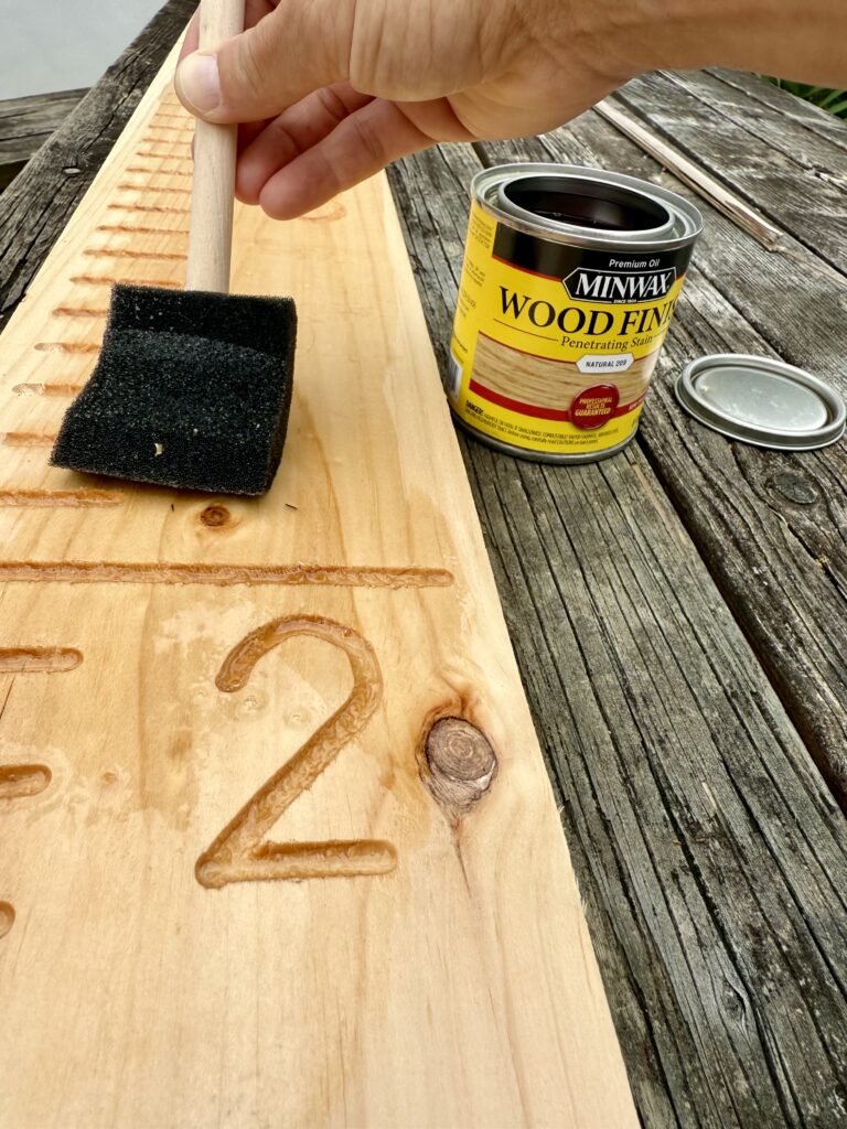 diy growth chart wood. Image of hand staining growth chart ruler on wooden table.