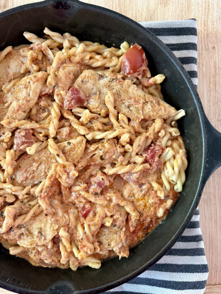 easy chicken dinner recipes. Image of Image of creamy bruschetta chicken in cast iron skillet on top of black and white cloth napkin on wood countertop 