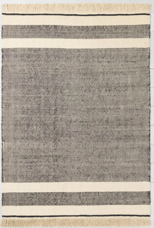 neutral affordable rugs. Image of jute rug with cream and black stripes and tassels.