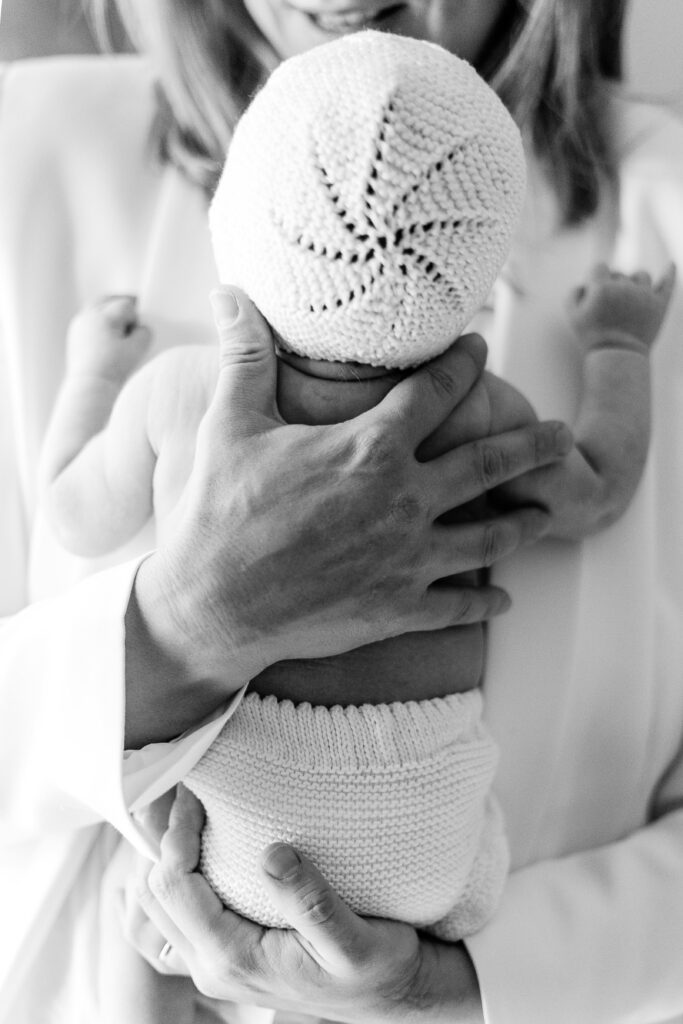 hospital bag checklist for moms to be. 
Black and white image of woman holding baby in diaper with crocheted hat.
