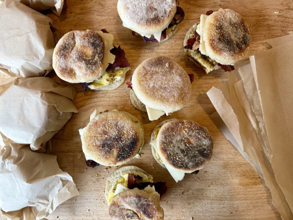 easy make ahead breakfast sandwiches. Picture of English muffin breakfast sandwiches on wood cutting board.