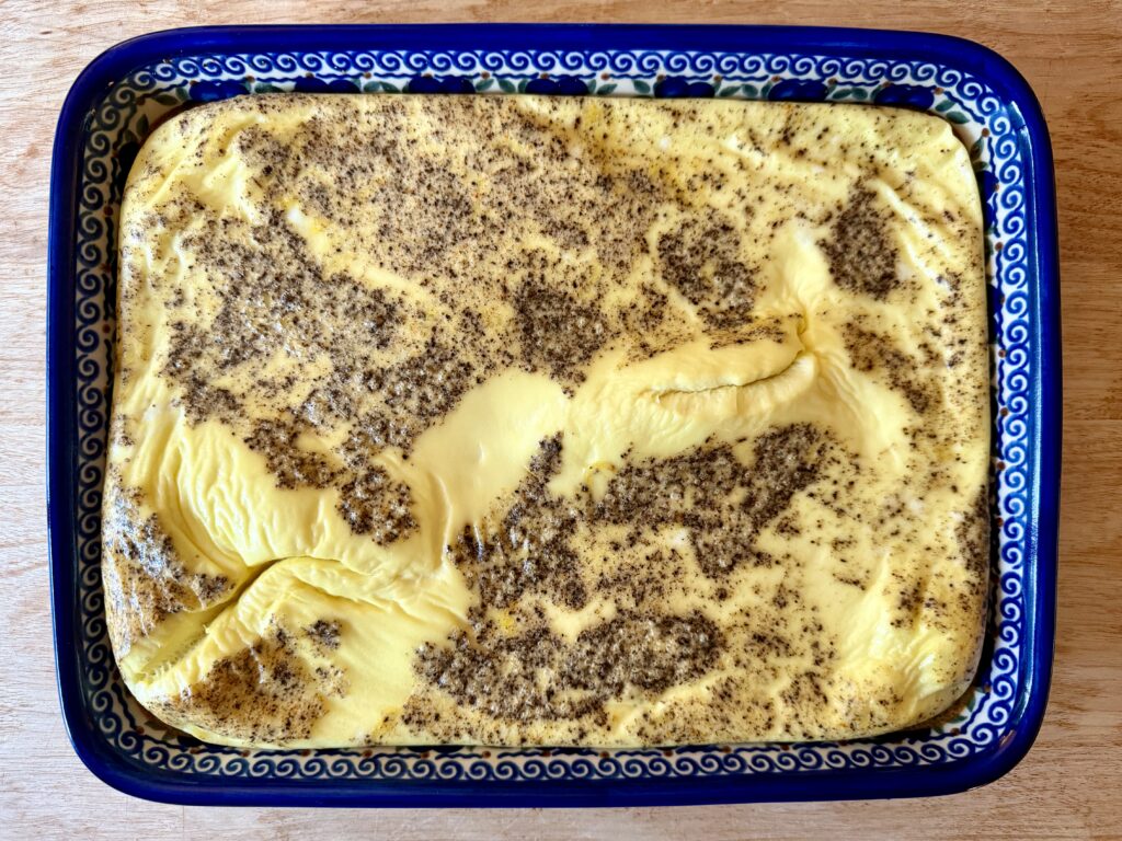 meal prep freezer breakfast sandwiches. Image of eggs cooked in polish pottery baking dish on wood countertop. 