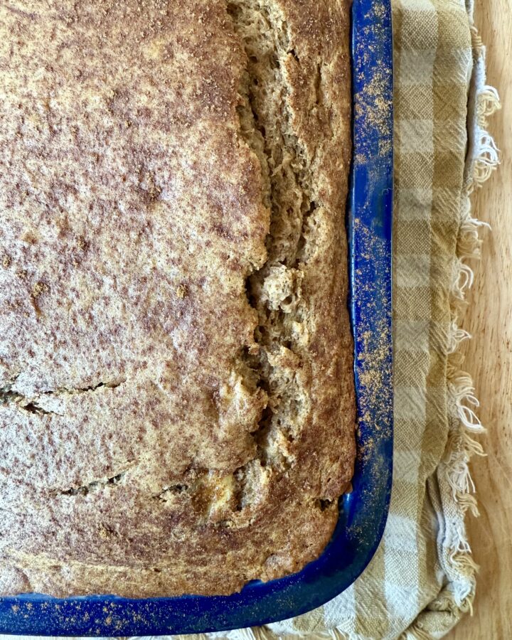 image of sourdough banana bread in blue loaf pan on tan and gingham cloth napkin.