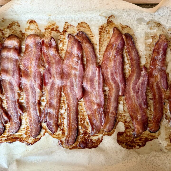 how to bake bacon in the oven. Image of cooked bacon on a sheet pan that is lined with parchment paper.