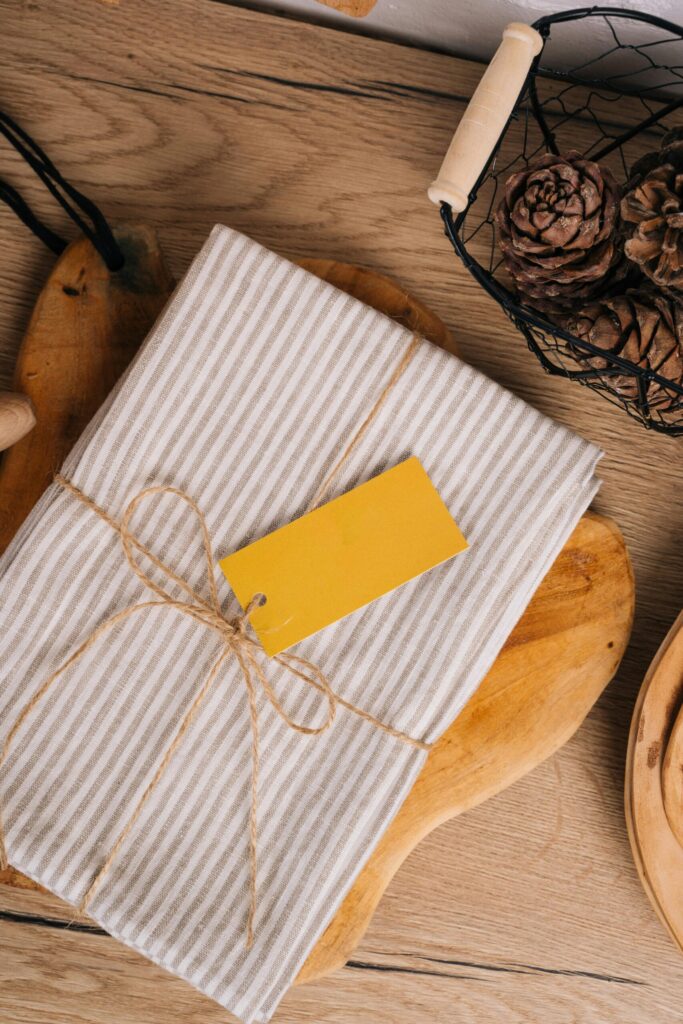 family traditions for kids. Image of folded striped towel wrapped in twine with yellow note on cutting board on wooden table. 