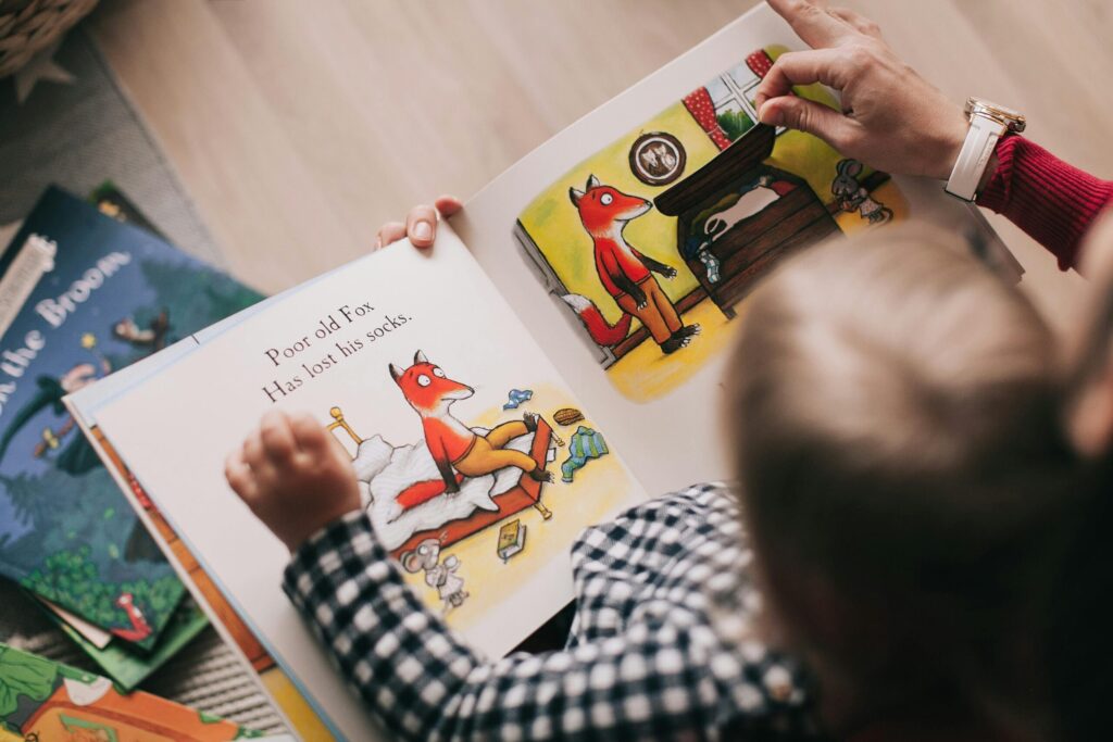 family traditions ideas Christmas. Image of toddler in woman's lap reading a book with images of a fox on pages of book. 