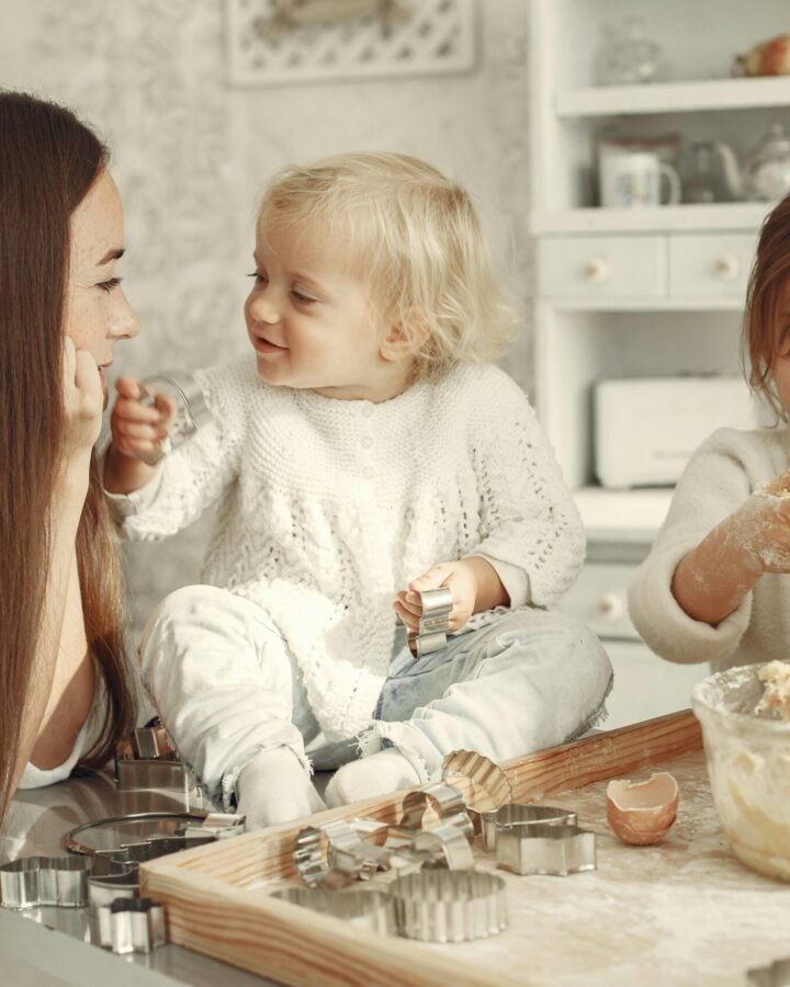 family traditions list. Image of mom and two daughters baking in kitchen. All three are dressed in white.