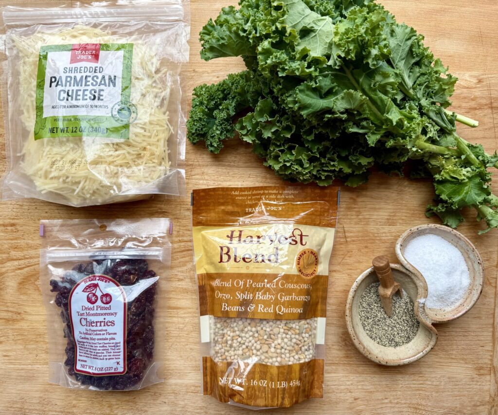  Image of ingredients for healthy winter kale salad - bag of parmesan cheese, bunch of green curly kale, bag of dried cherries, bag of grains, and ceramic container with salt and pepper.