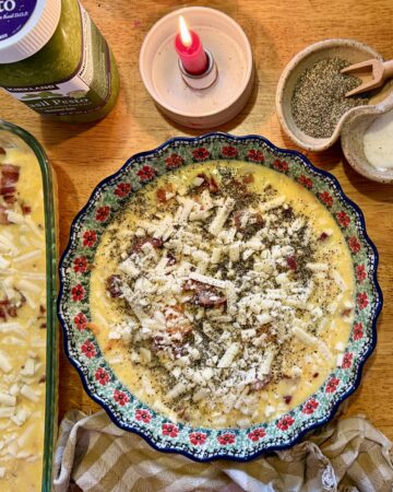 meal prep. Image of egg casserole, quiche, grated potato, pesto, salt and pepper, and a lit candle on a wooden table.