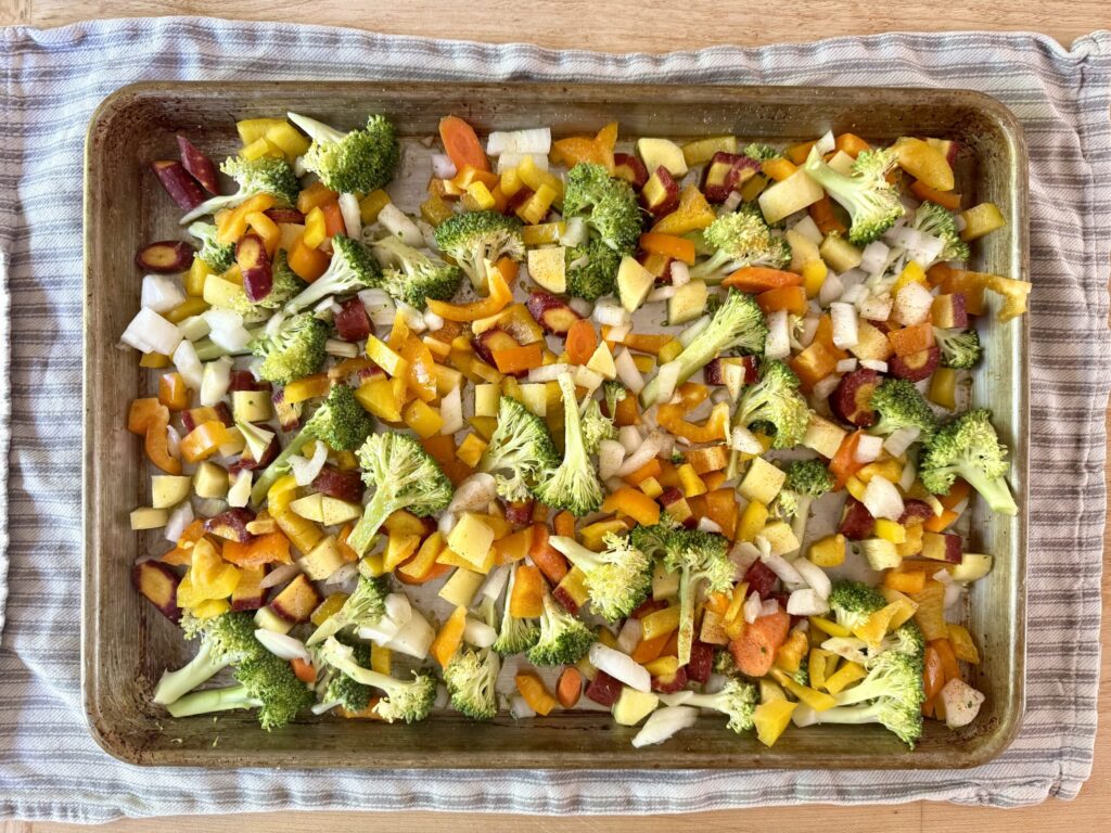 meal prep hacks Image of chopped vegetables in a sheet pan on a striped dish towel.