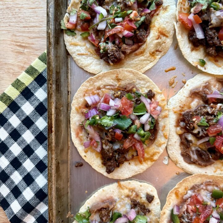 image of sheet pan tacos with ground beef and pico de gallo on sheet pan with black and white checkered dish towel.