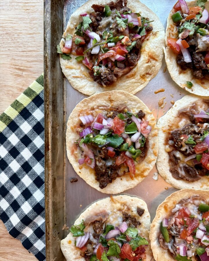 image of sheet pan tacos with ground beef and pico de gallo on sheet pan with black and white checkered dish towel.