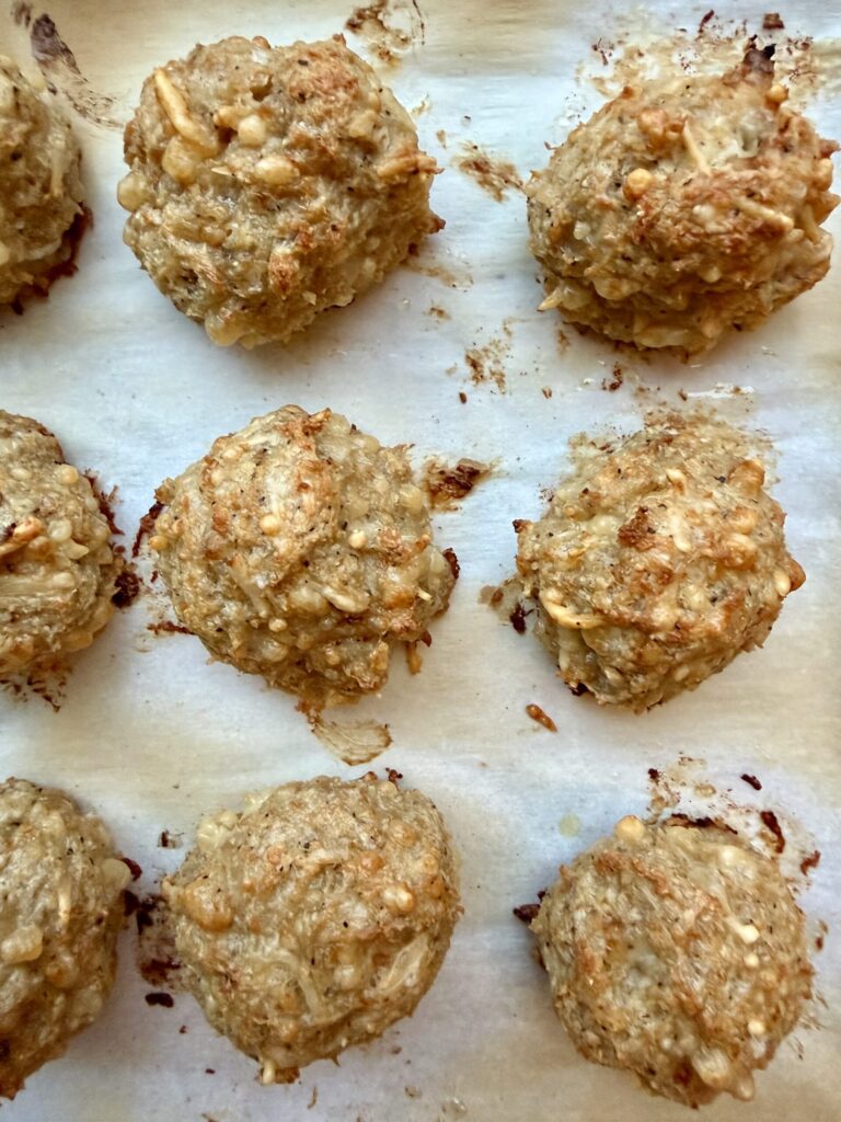 chicken parmesan meatballs recipe, closeup image of chicken parmesan meatballs on parchment paper.