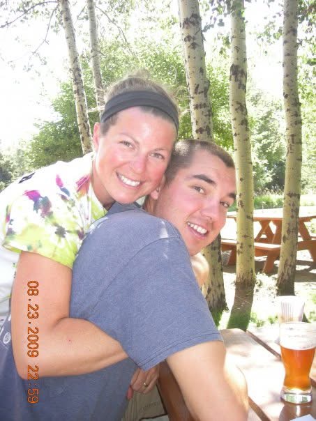 friend support after loss. Image of woman hugging man in forest at a picnic table.