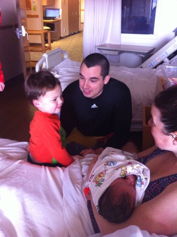 how to show up for friend after loss. Image of woman in hospital bed holding newborn, with toddler son, and father.