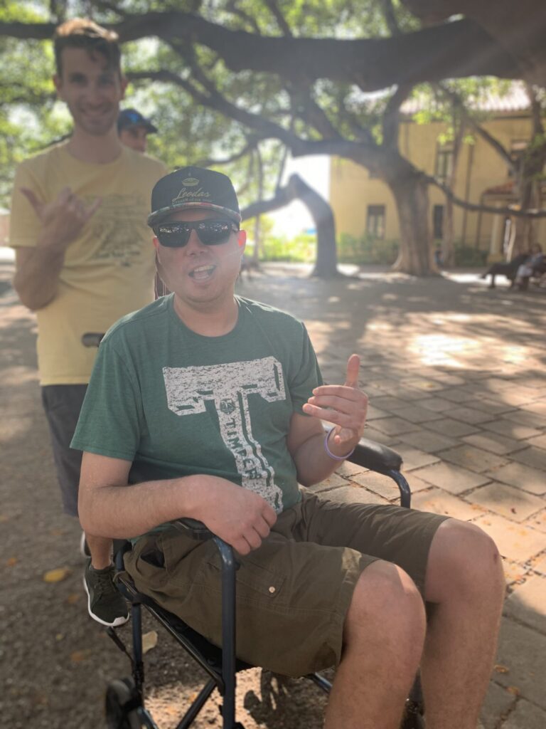 Image of man in wheel chair in green shirt and shorts.