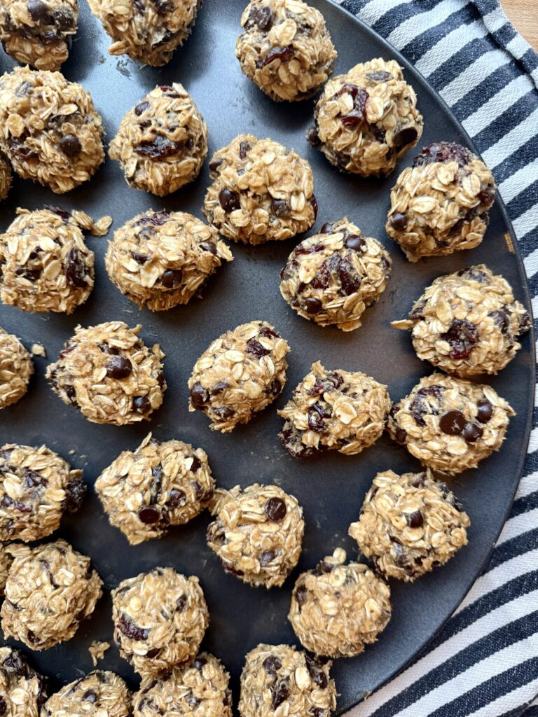 Image of no-bake peanut butter oatmeal energy balls on black circular sheet pan on black and white striped cloth napkin. 