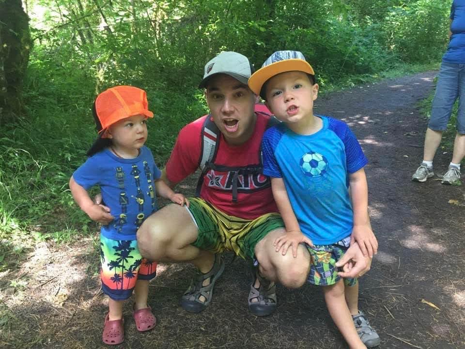 support friend through loss. Image of man with two sons. All three are wearing t shirts, shorts, and hats. 